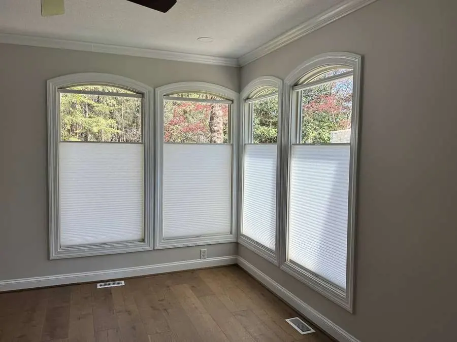 Honeycomb shades installed on arched windows in a Carolina sunroom